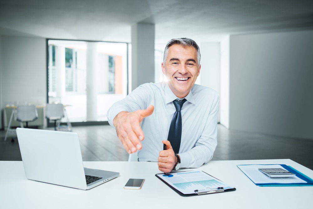 Smiling confident businessman giving an handshake, agreement and recruitment concept